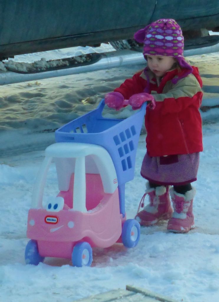 Toddler pushing a toy through snow